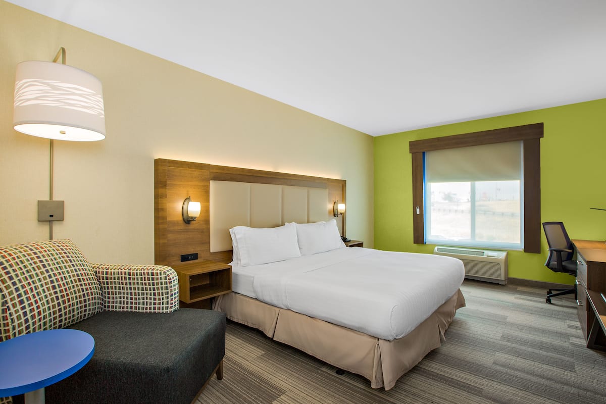 Una habitación de hotel con cama, escritorio, silla, sofá y una mesita.