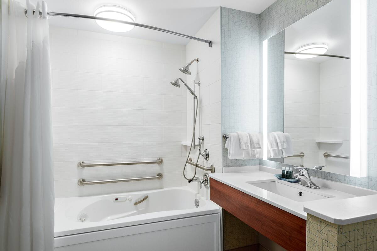 Un baño moderno con bañera, ducha, tocador y un espejo grande.
