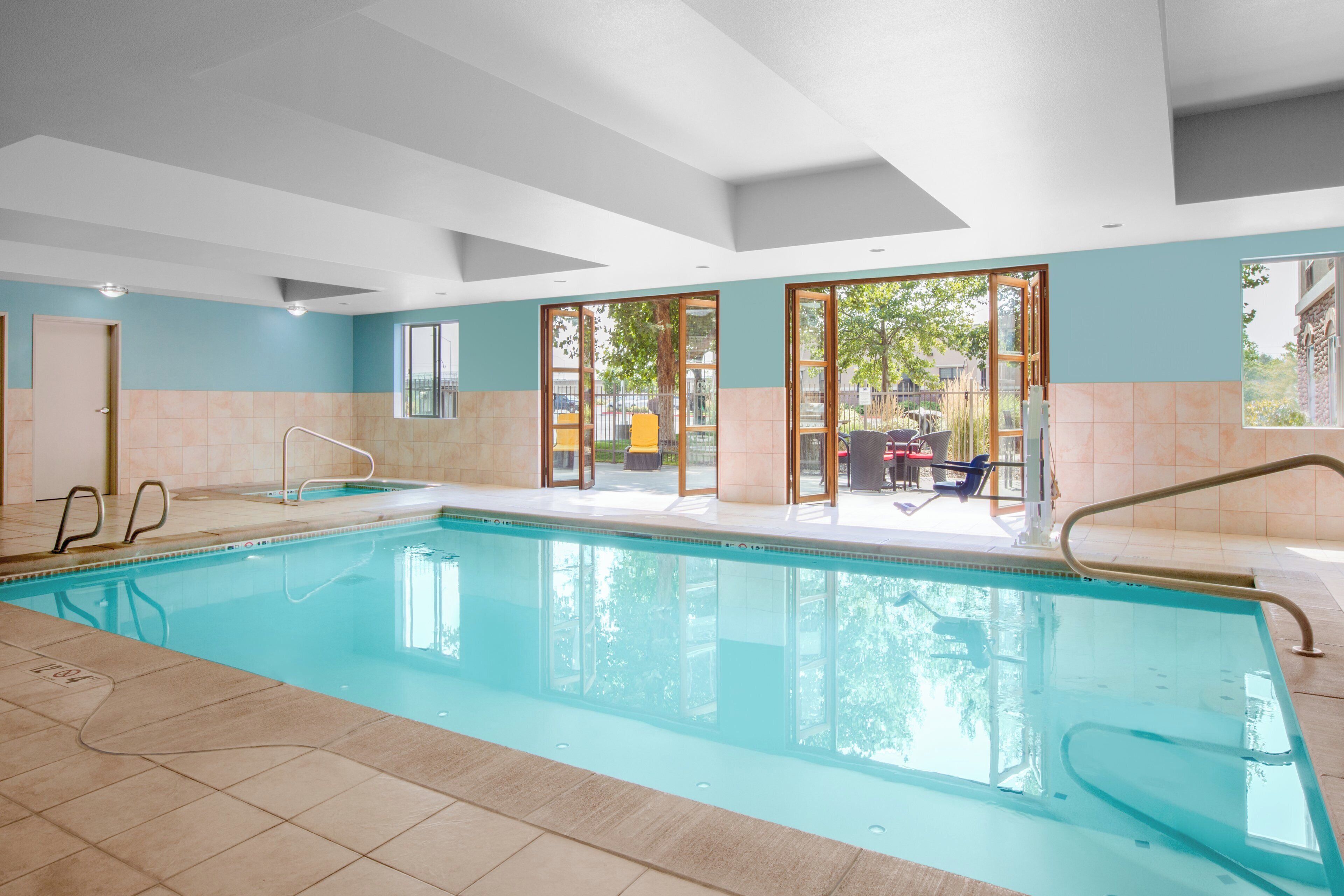 A swimming pool with clear water, surrounded by a tiled deck.