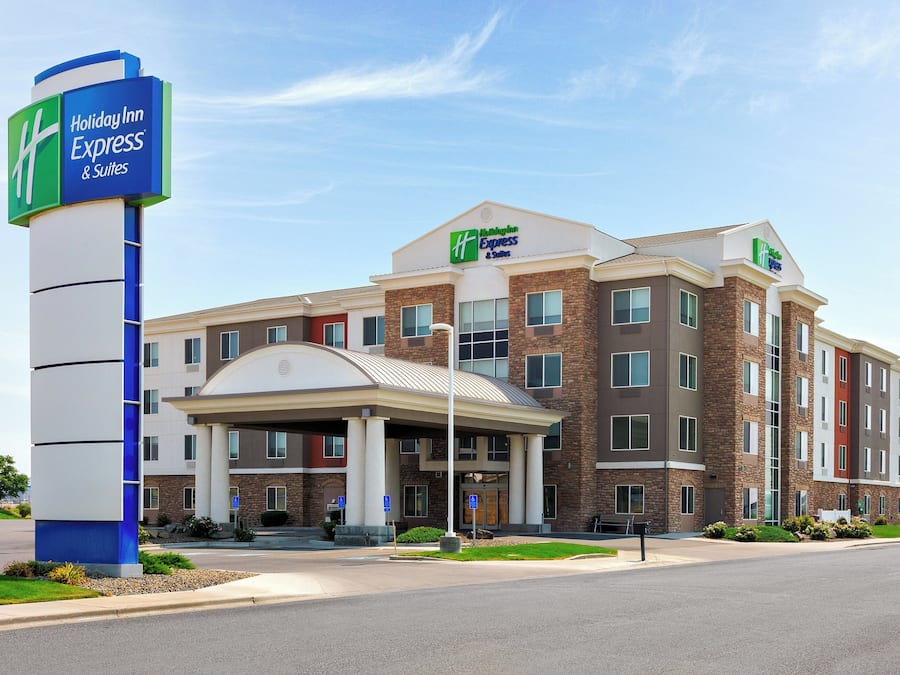 A Holiday Inn Express & Suites hotel with a modern brick facade, multiple entry points, and a clear sky.