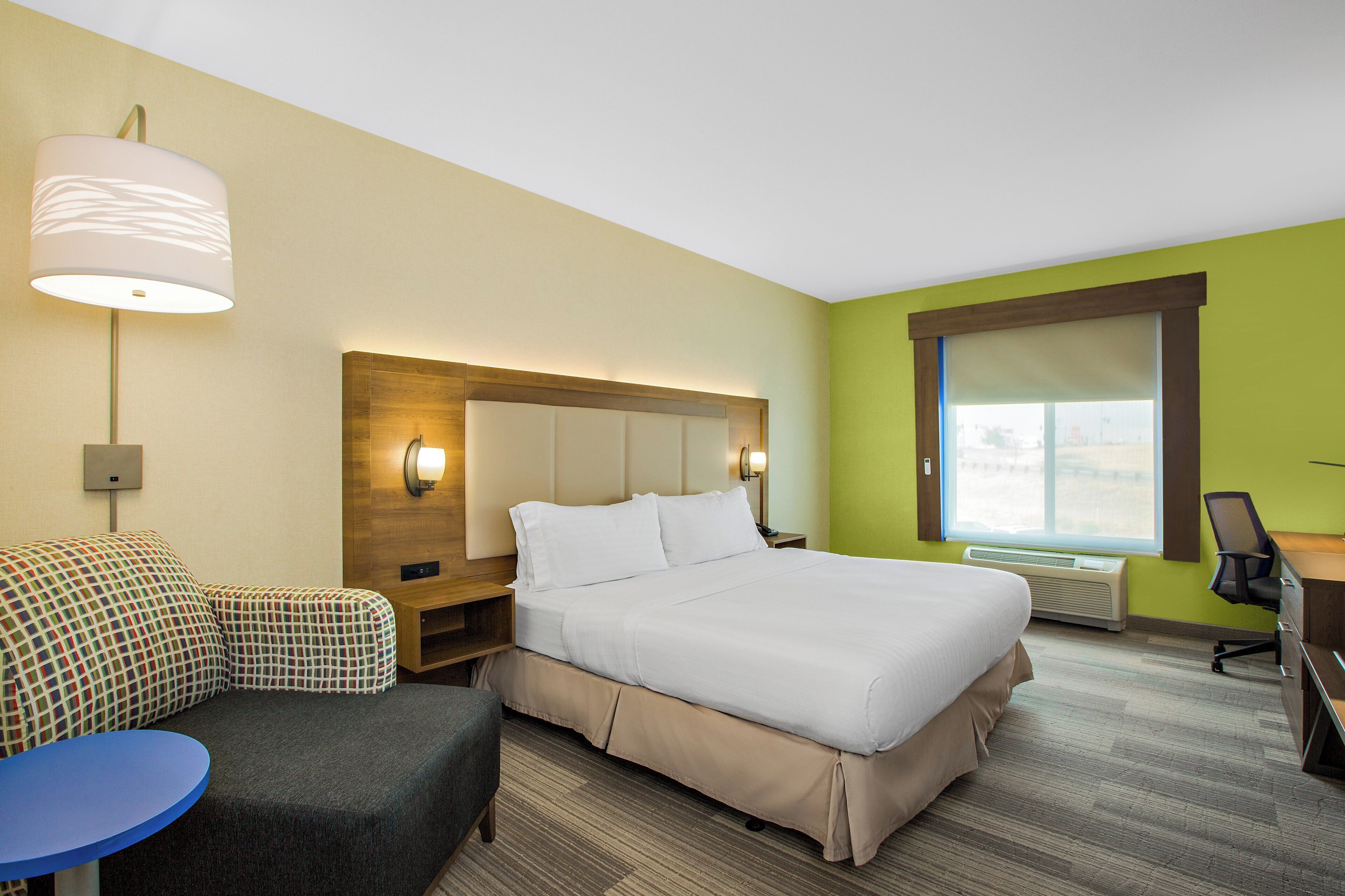 Ein Hotelzimmer mit einem Bett, einem Schreibtisch, einem Stuhl, einem kleinen Tisch und einem Fenster.