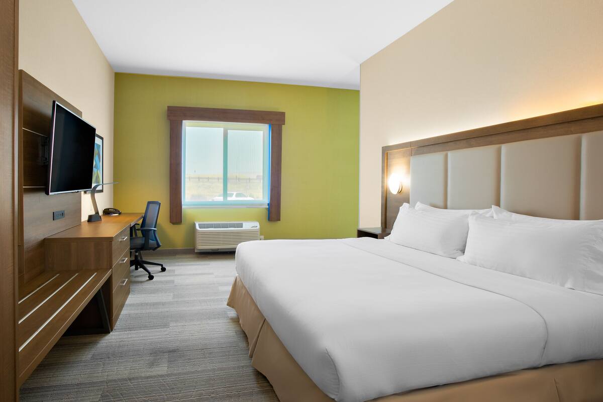 Habitación de hotel con cama, escritorio, silla, televisor y ventana con vistas.