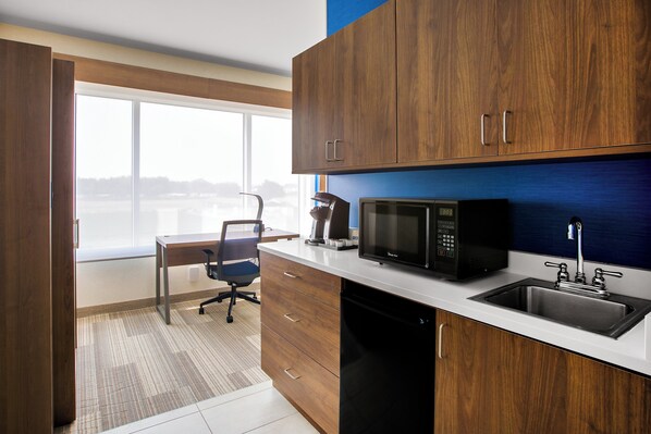 Una cocina moderna con armarios de madera, microondas, un lavamanos y una ventana con vistas a un paisaje nevado.