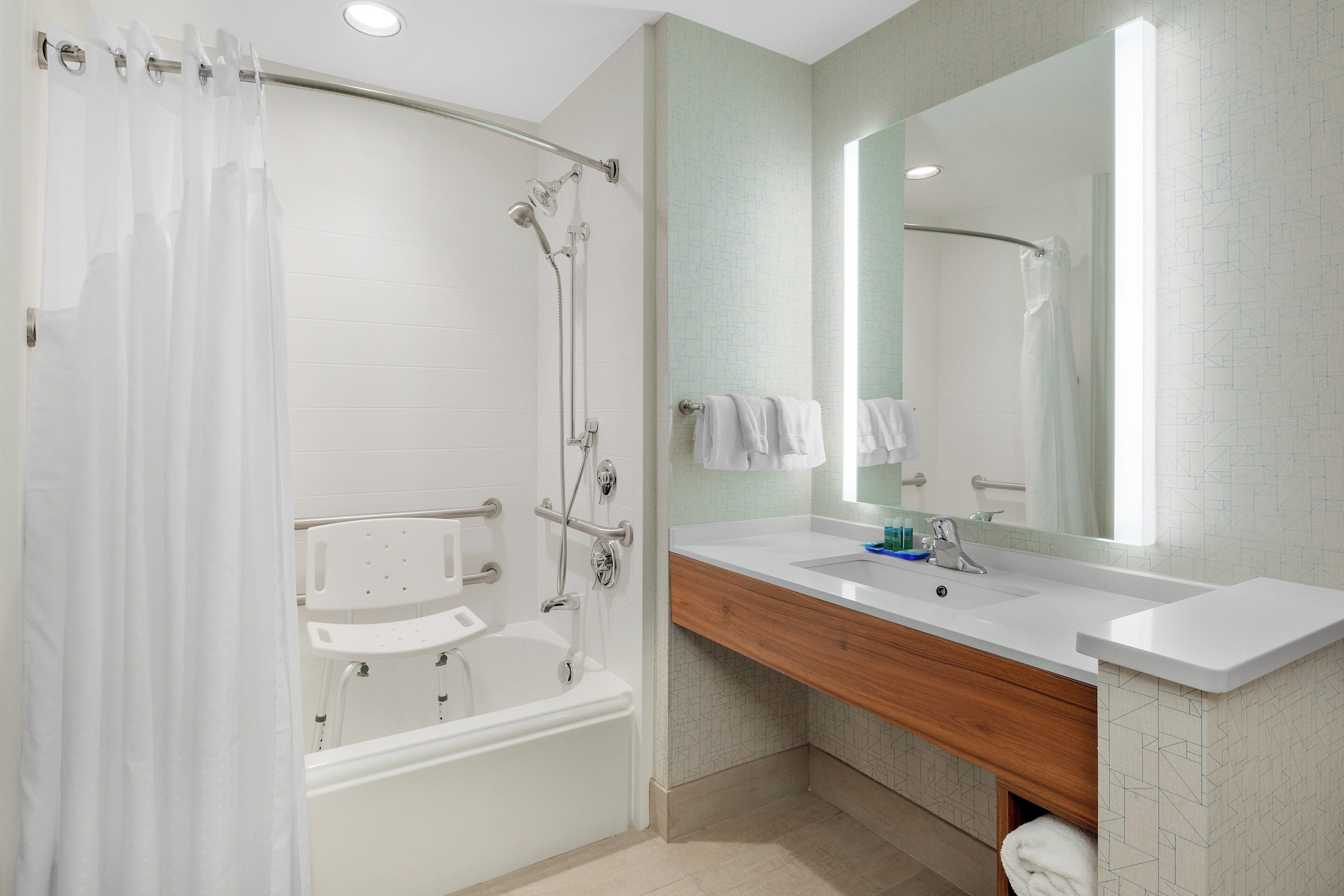 A modern bathroom with a bathtub, shower, and vanity with a mirror.