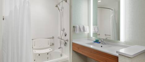 A modern bathroom with a bathtub, shower, and vanity with a mirror.