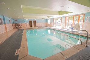 Une piscine dotée d’une plage carrelée, d’un poste de surveillance pour les sauveteurs et d’un panneau indiquant la présence d’un dispositif d’élévation pour faciliter l’accès à la piscine.