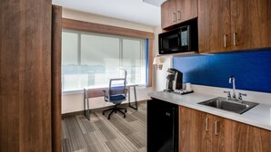 A modern kitchen with wooden cabinets, a microwave, a sink, and a coffee maker.