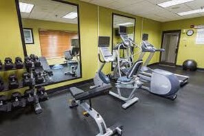 A gym with exercise equipment, a mirror, and a wall-mounted clock. - Holiday Inn Express McComb by IHG (McComb)