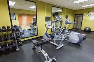 Un gimnasio con equipo de ejercicio, un espejo y un reloj en la pared.