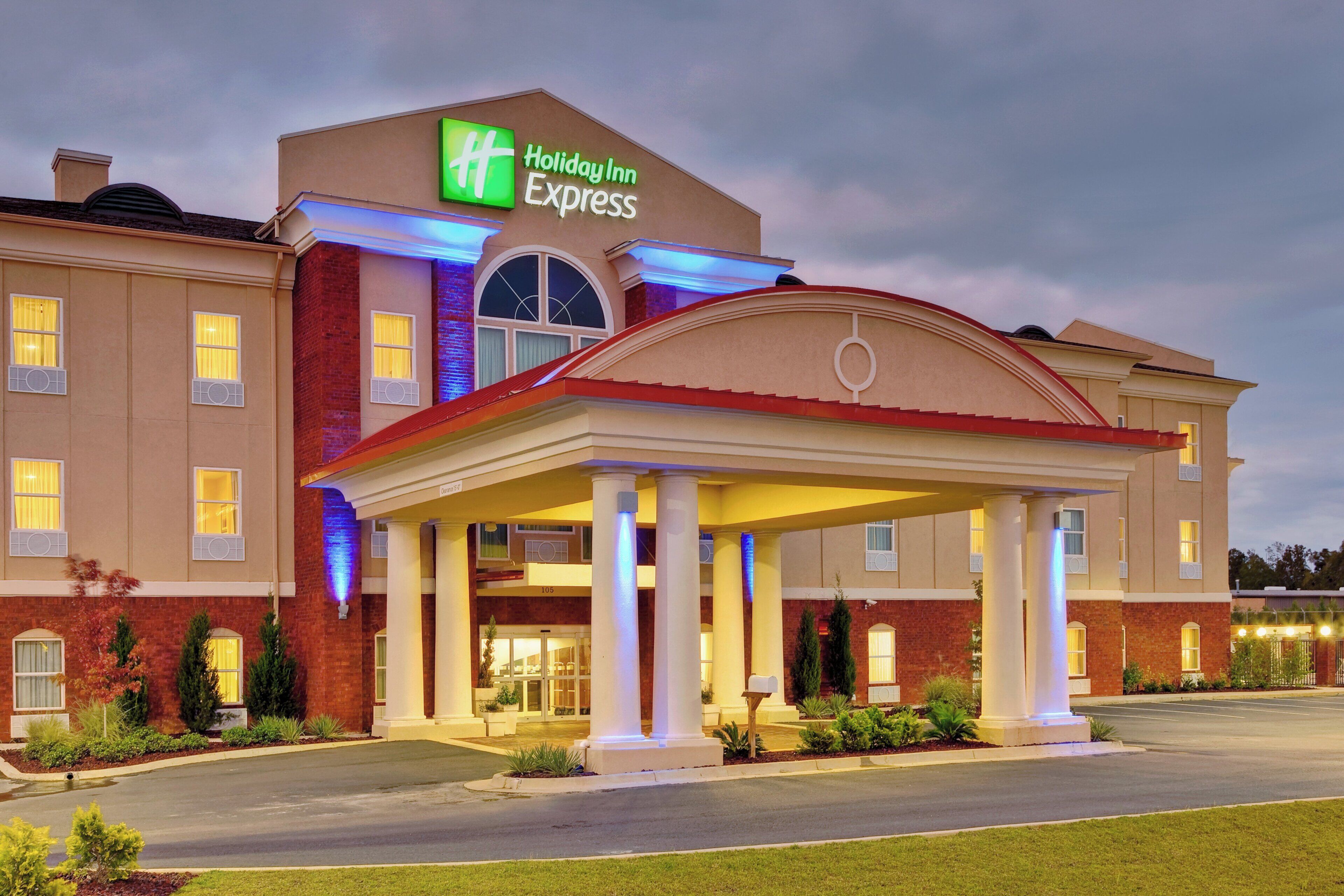 A Holiday Inn Express hotel with a covered entrance, brick facade, and a well-lit sign.