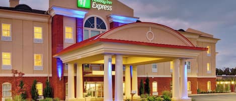 Un hotel Holiday Inn Express con ingresso coperto, facciata in mattoni e insegna ben illuminata.
