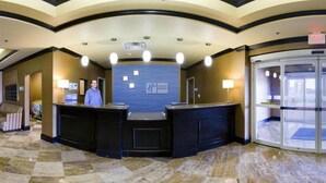 Zona de recepción de un hotel con techo curvo, una recepcionista, mostrador de recepción y puerta giratoria.