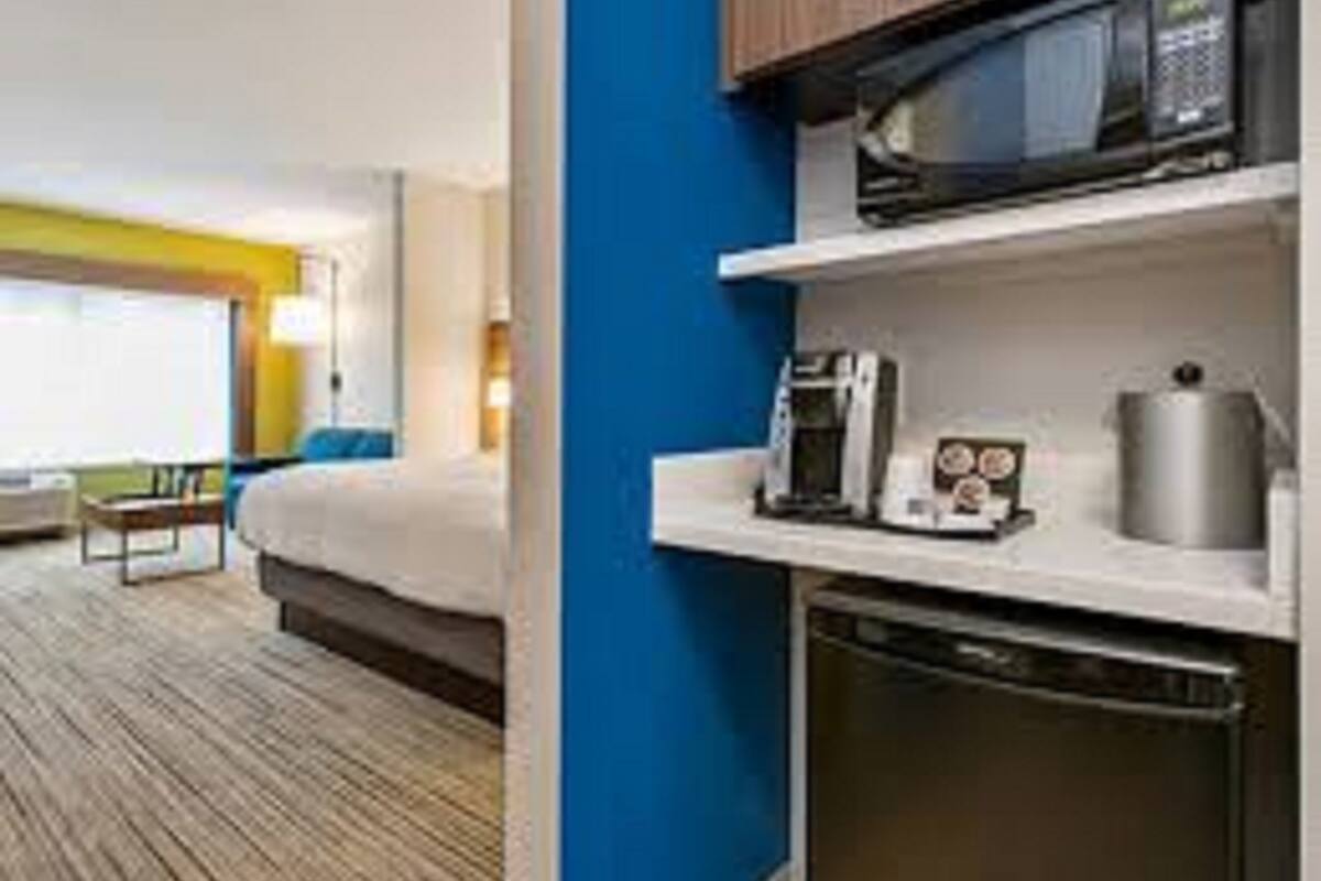A hotel room with a bed, a coffee maker, a microwave, and a dishwasher.