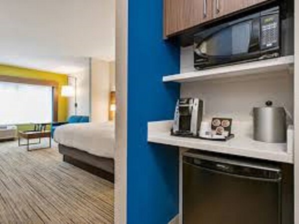 A hotel room with a bed, a coffee maker, a microwave, and a dishwasher.