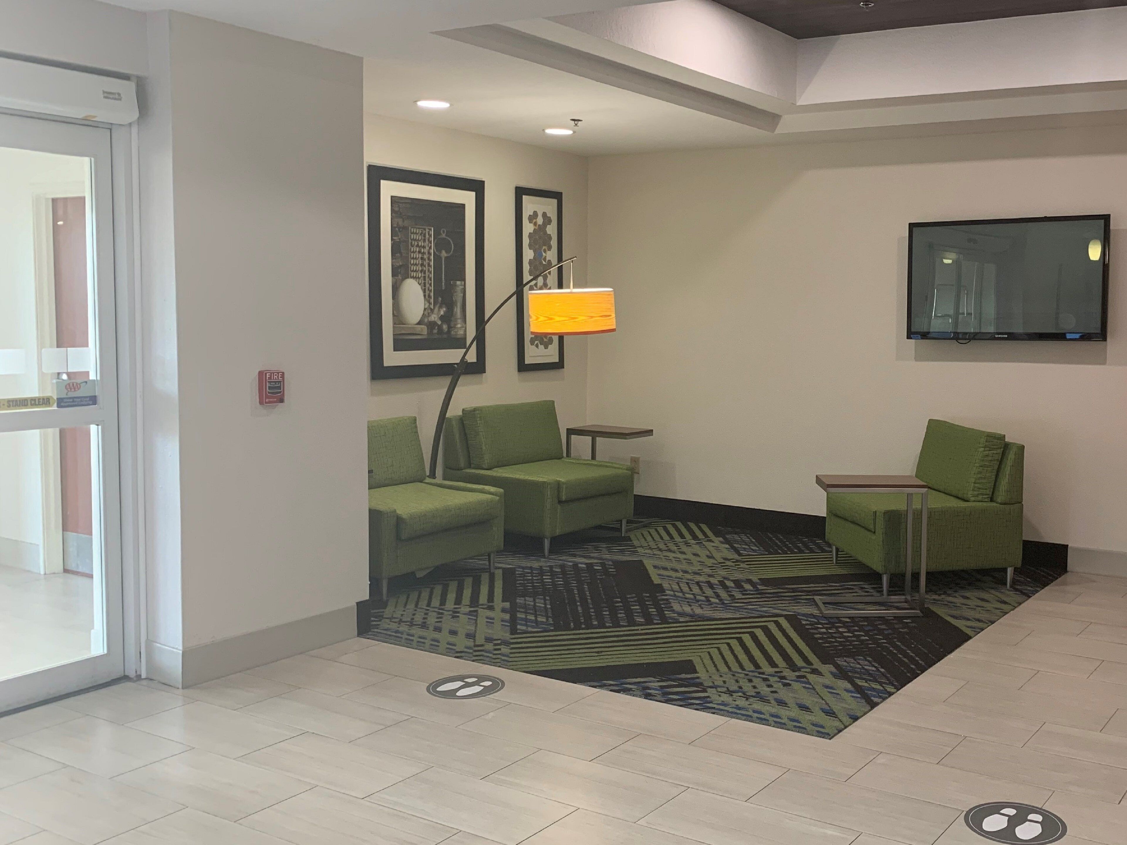 A hotel lobby with green seating, a flat-screen TV, and a patterned carpet.