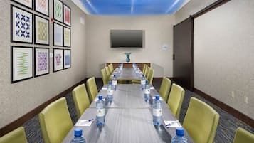 A conference room with a long table, yellow chairs, and water bottles.