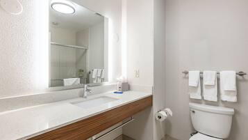 A bathroom with a white sink, mirror, and toilet.