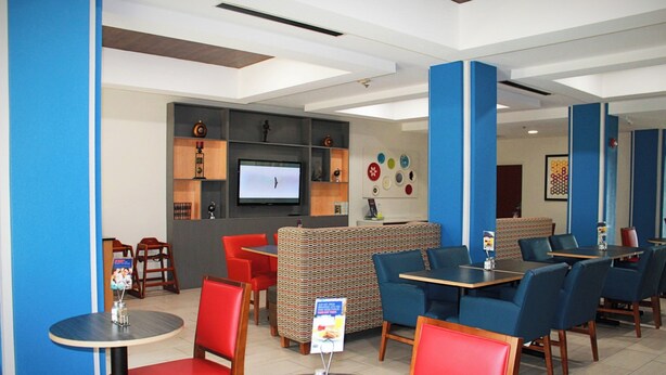 Un restaurante moderno con asientos rojos y azules, un televisor y una barra.