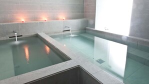 Un área de spa con tres piscinas separadas, cada una con un pequeño banco y una vela.