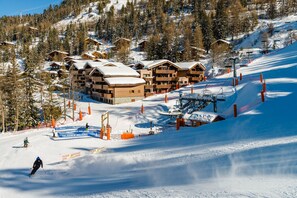 Un centro de esquí con cabañas de madera, un telesilla y una pista cubierta de nieve.