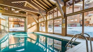 An indoor swimming pool with wooden beams and large windows. - Résidence Lagrange Vacances Les Chalets Edelweiss (La Plagne-Tarentaise)