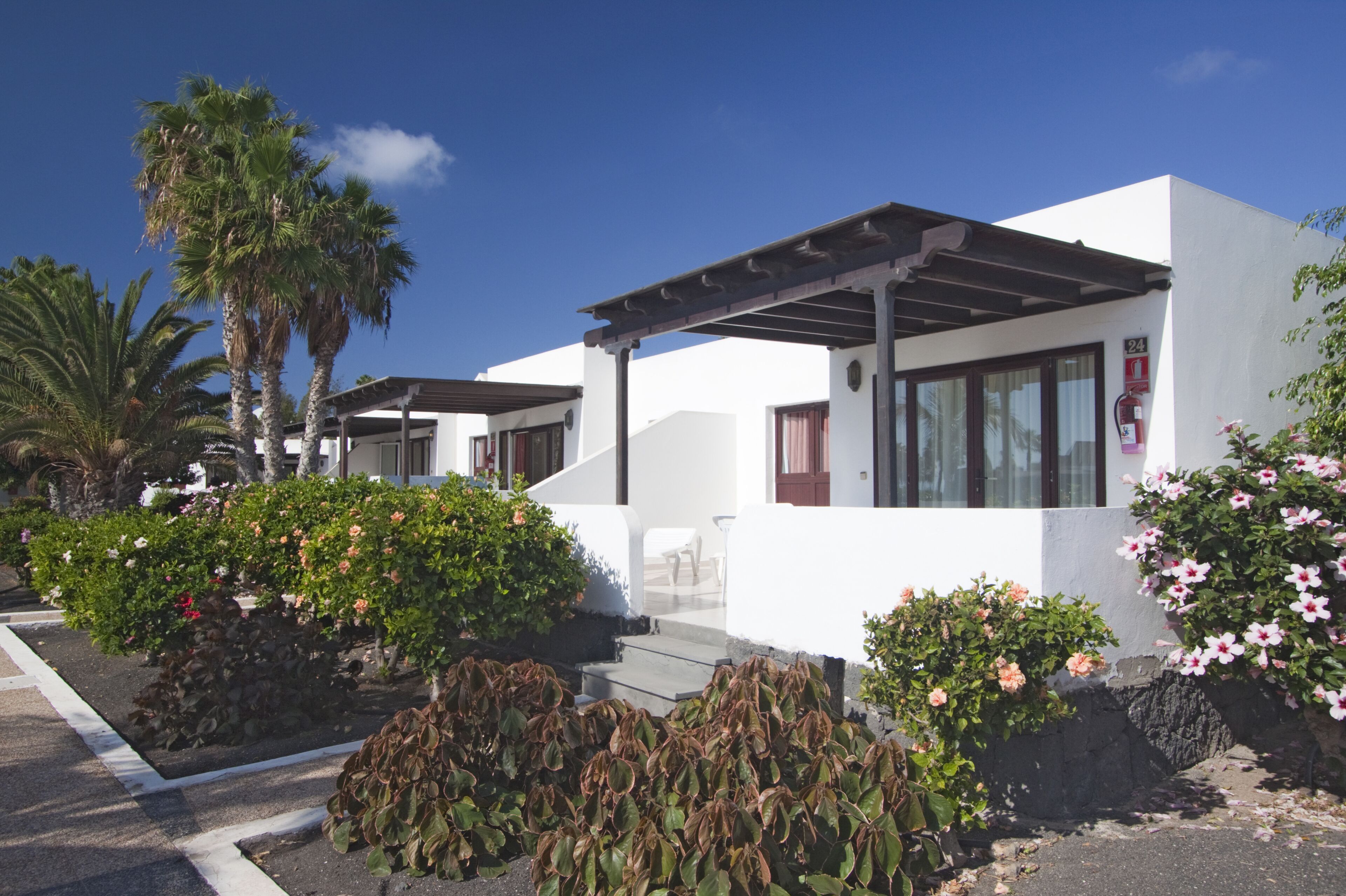 A modern building with a white facade, a covered patio, and a fire extinguisher mounted on the wall.