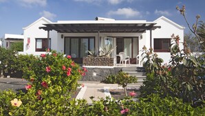 A modern white building with a stone facade, large windows, and a covered patio area.