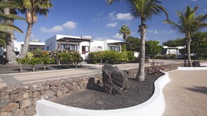 A modern building with a stone wall and palm trees in the foreground.