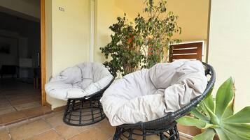 Two wicker chairs with cushions on a tiled patio.