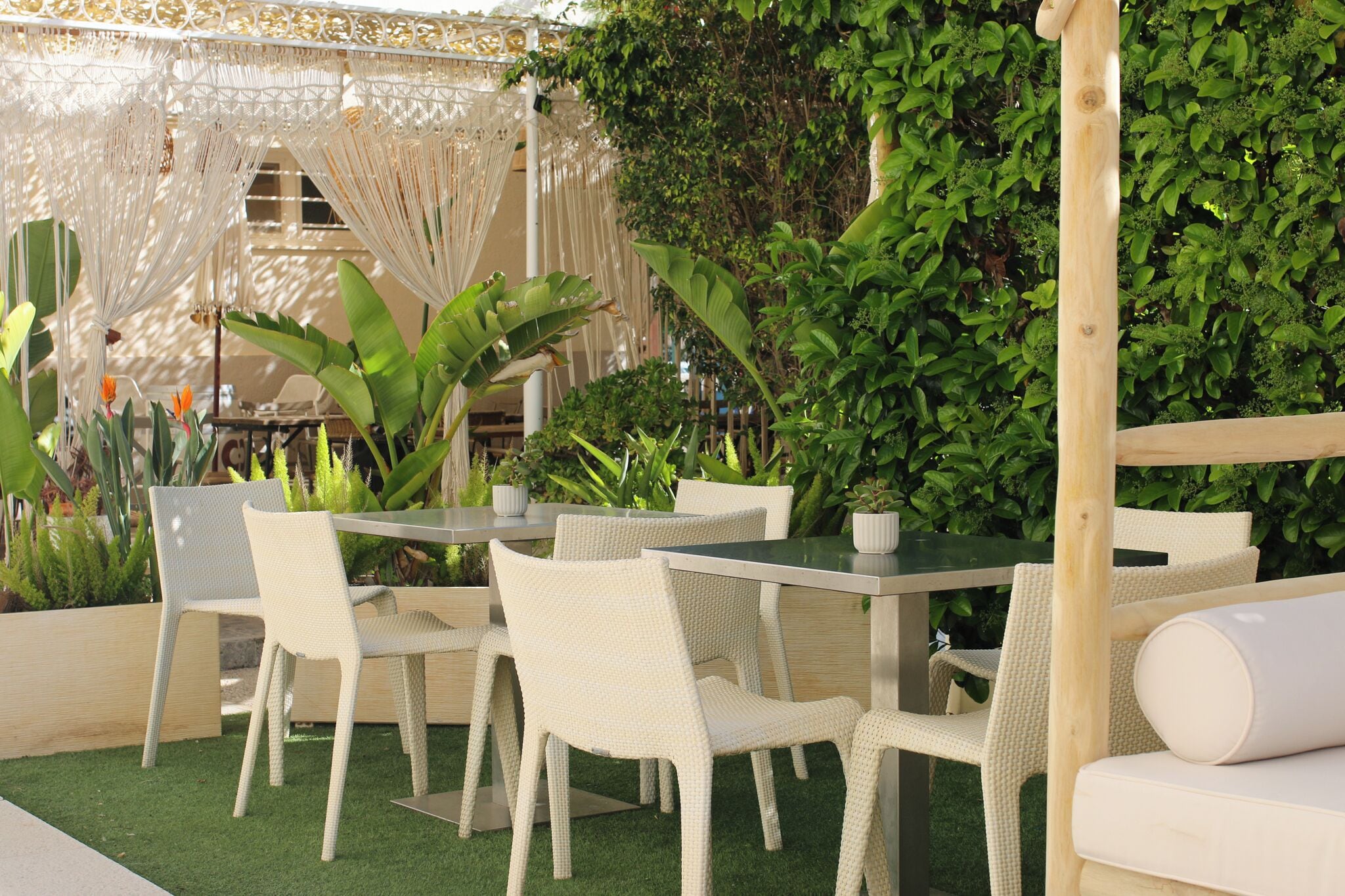 An outdoor seating area with white wicker furniture and a green artificial turf floor.