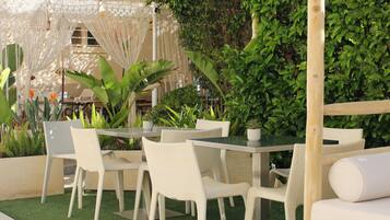 An outdoor seating area with white wicker furniture and a green artificial turf floor.