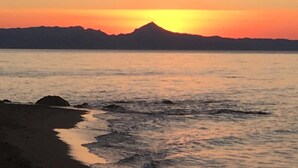 A sunset over a calm sea with a mountain silhouette in the distance. - Hotel Rhys Denia - Only Adults (Denia)