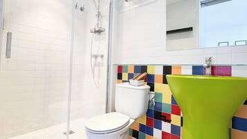 Un baño moderno con cabina de ducha de vidrio, inodoro blanco y suelo de baldosas de colores.