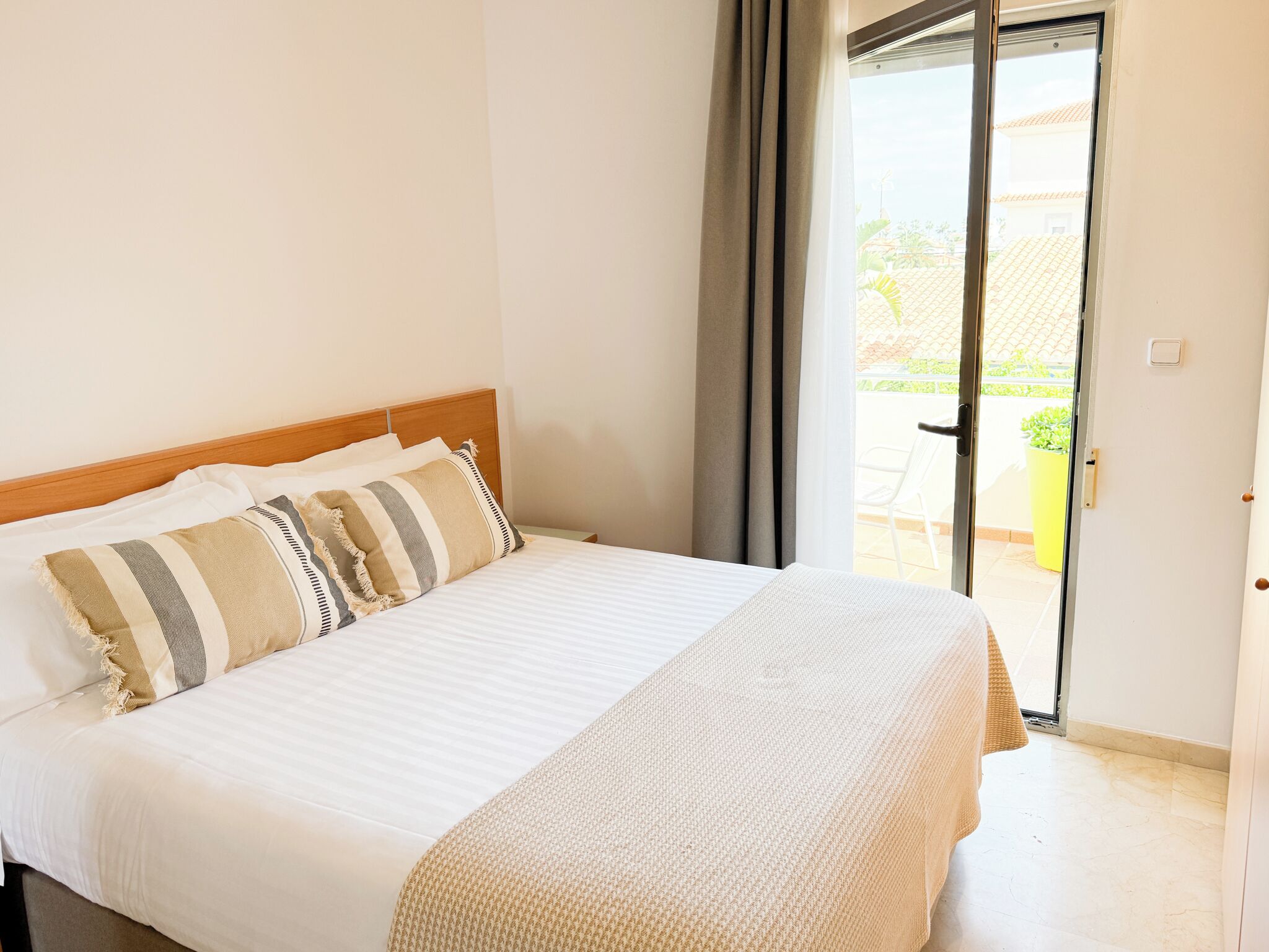Ein Hotelzimmer mit Bett, Blick ins Freie und Zugang zum Balkon.