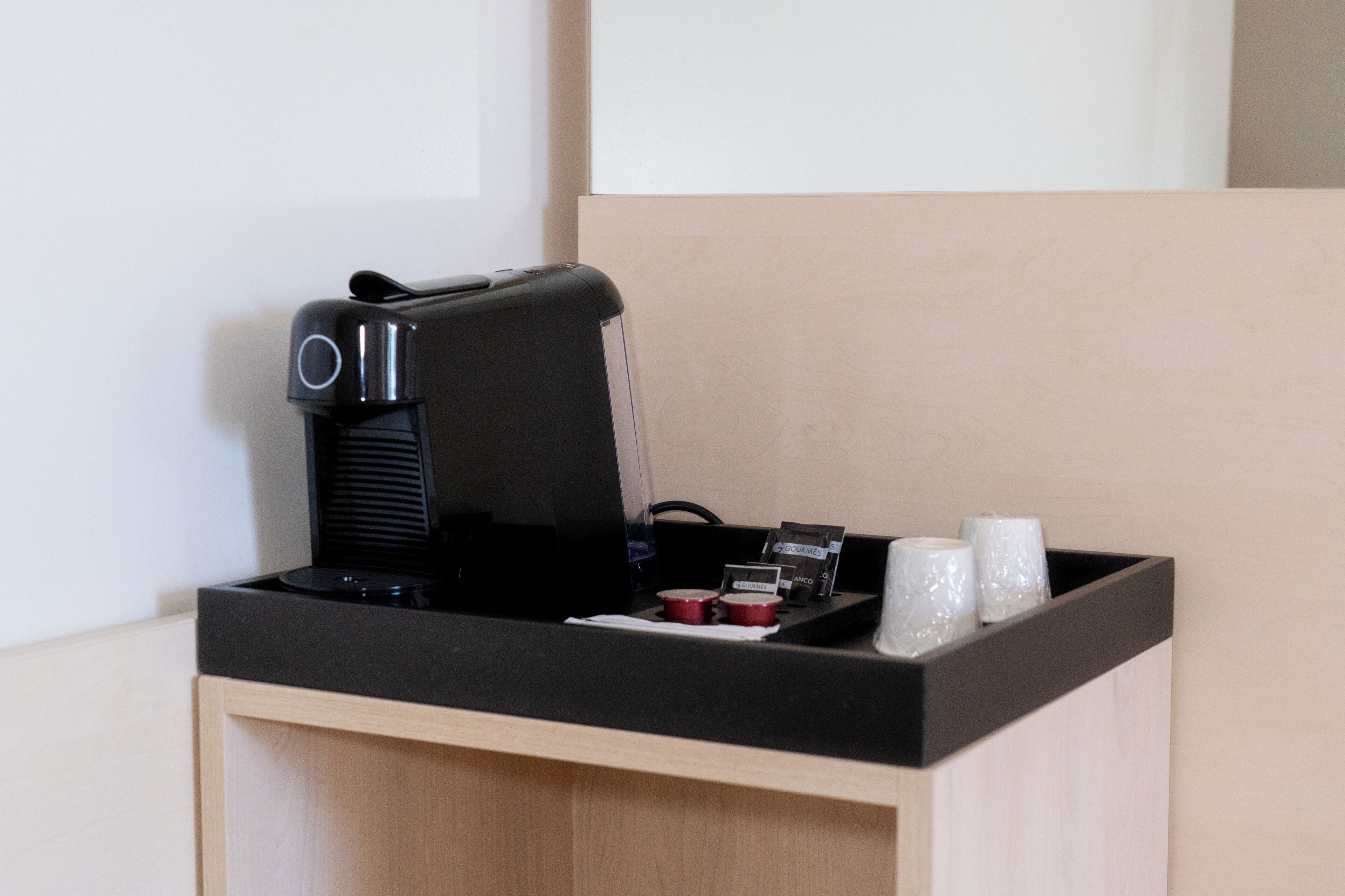 Una cafetera, un pequeño recipiente y dos tazas sobre una encimera.