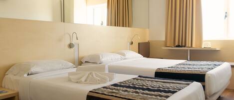A hotel room with two beds, a bedside table, a mirror, a window with curtains, and a flat-screen TV.