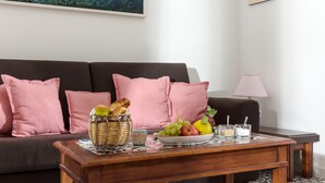 A living room with a sofa, a coffee table with fruits and a basket, and a lamp.