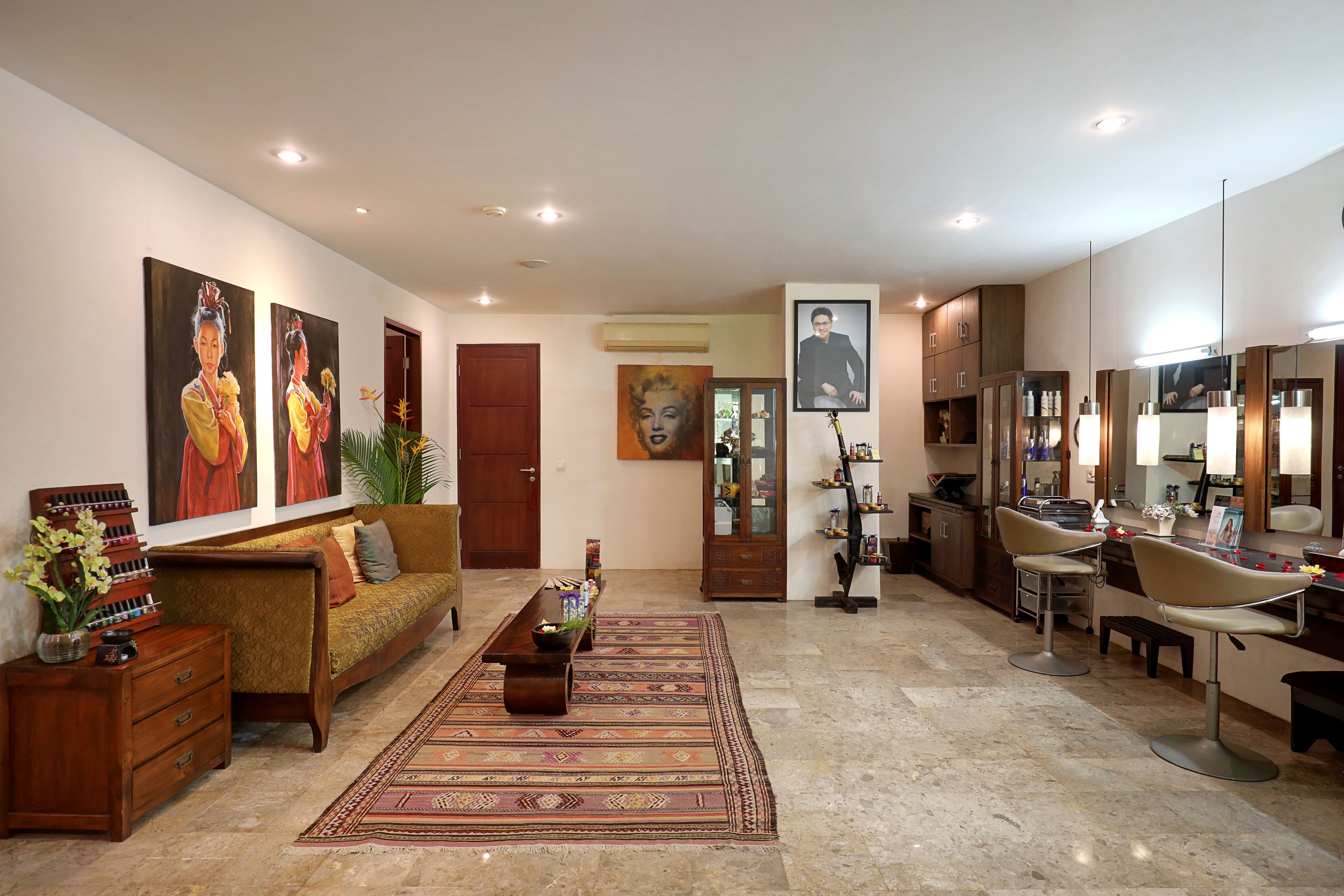 A spacious living area with a sofa, coffee table, and a dining table. There are two chairs, a cabinet, and a mirror.