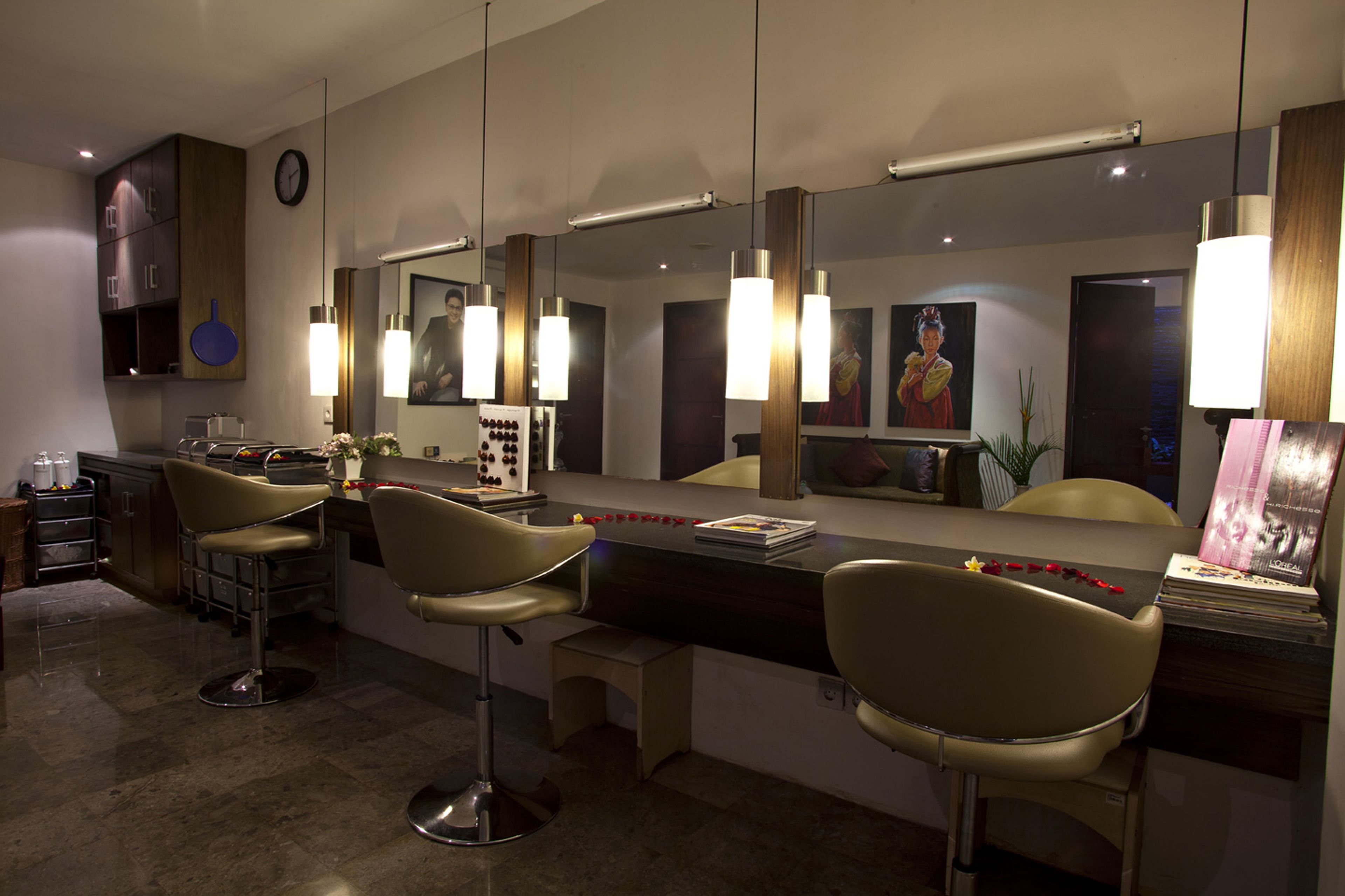 A modern bar area with three bar stools, a counter with a mirror, and pendant lighting.