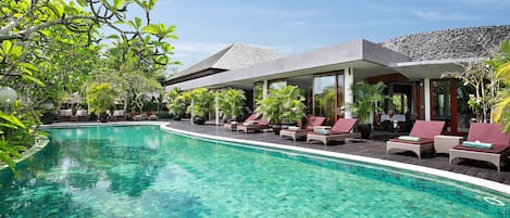 Una piscina al aire libre, sombrillas, sillones reclinables de piscina