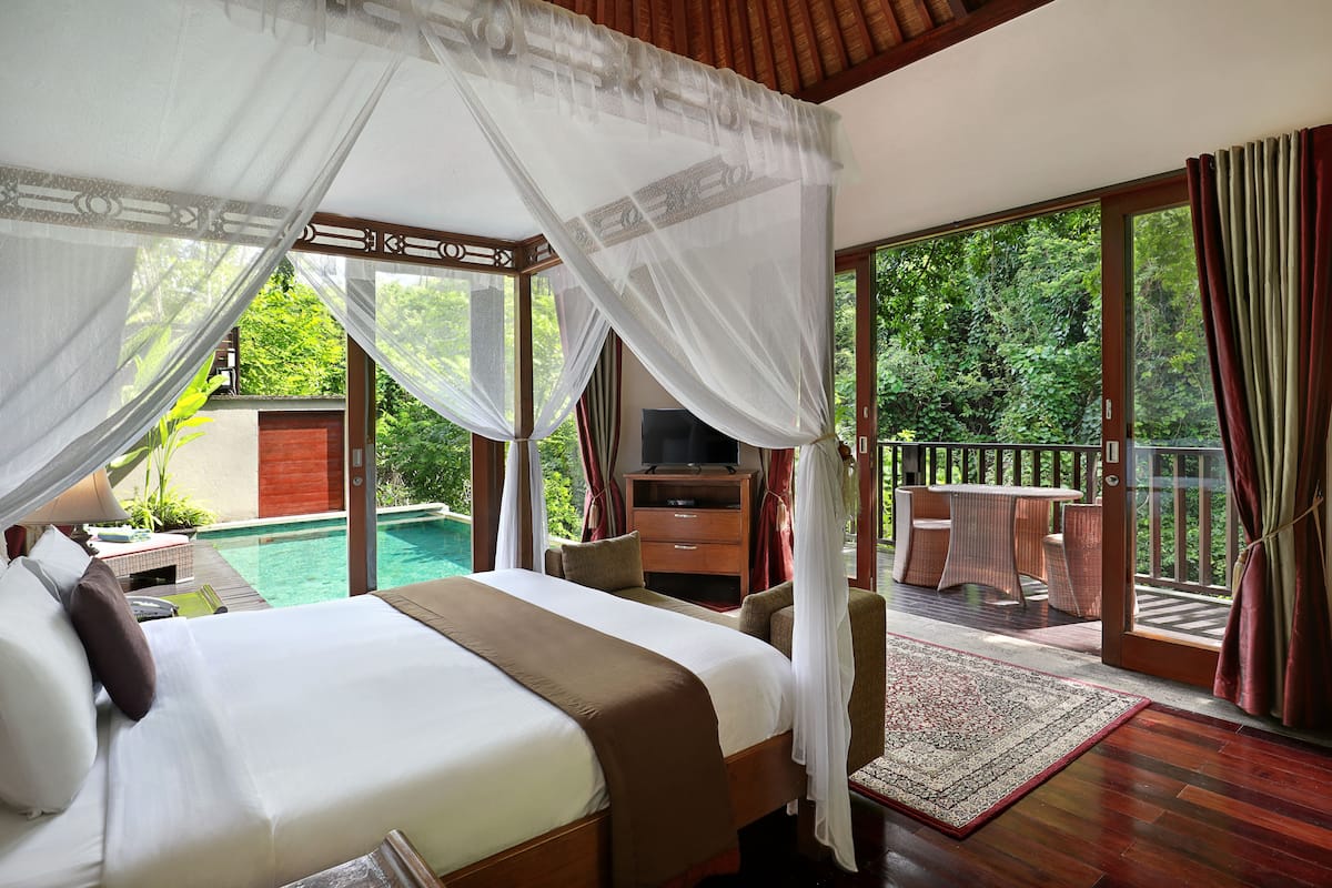 Une chambre avec un grand lit, une télévision et une vue sur une piscine et un jardin.
