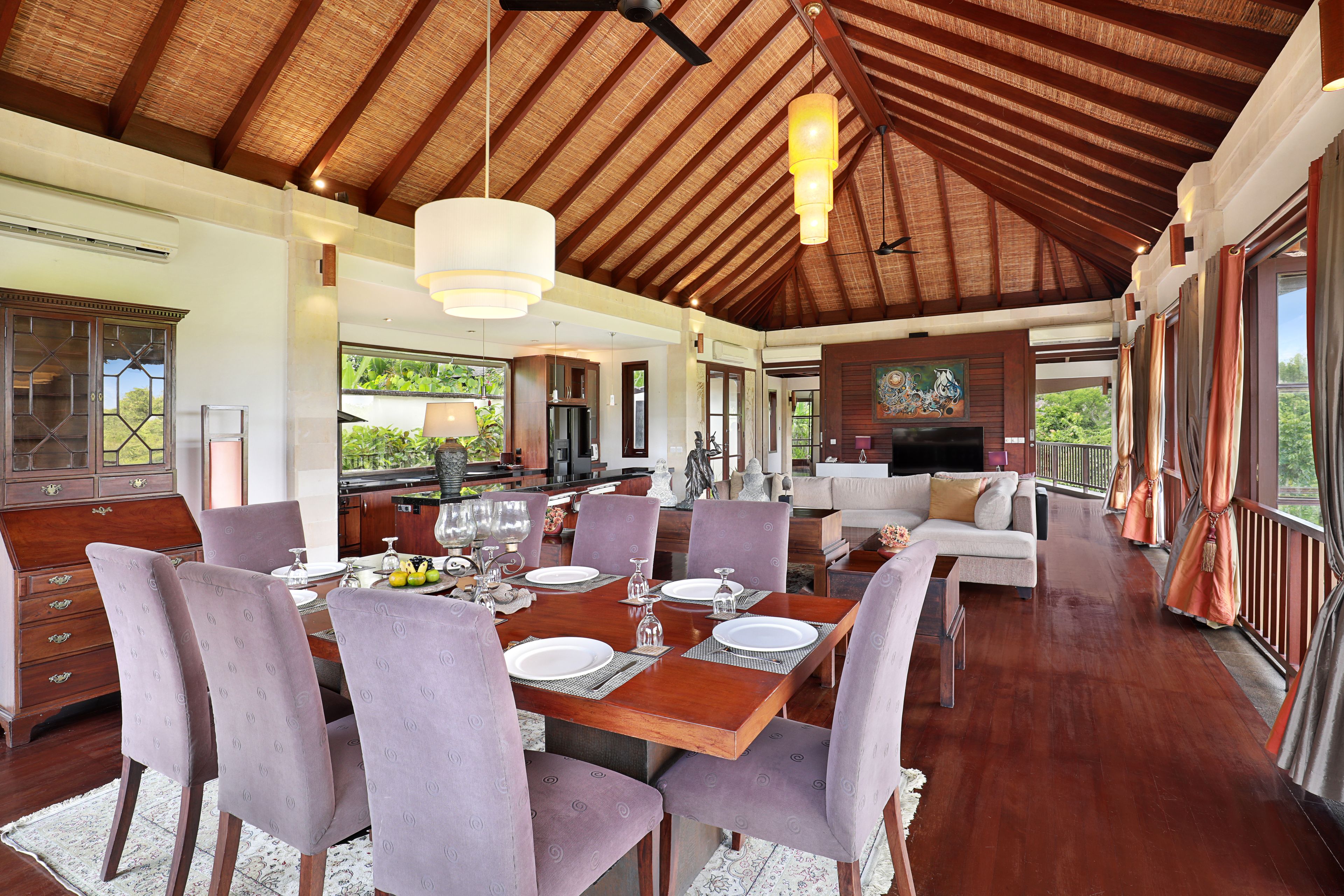 Un comedor espacioso con una mesa de madera, sillas moradas y un ventanal con vistas al exterior.