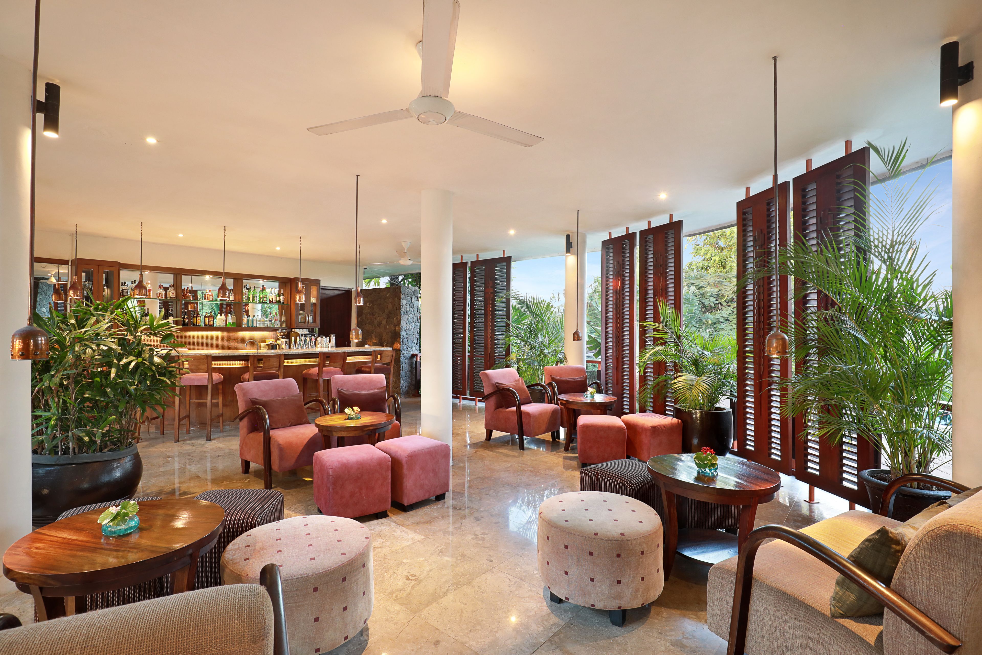 A spacious lobby with a bar area, comfortable seating, and large potted plants.