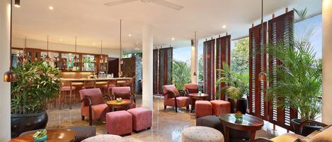 Un hall d’entrée spacieux avec un bar, des sièges confortables et de grandes plantes en pot.
