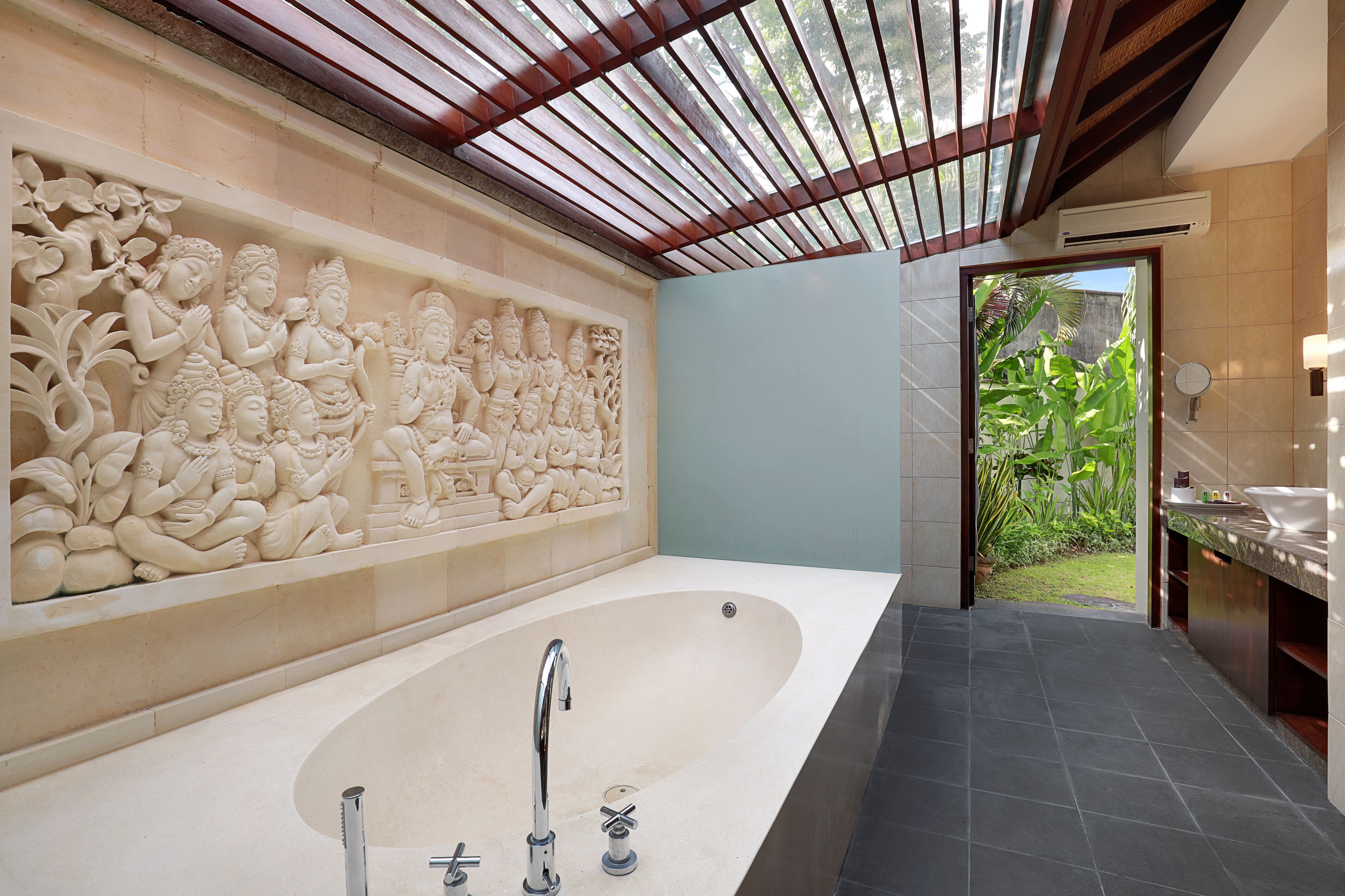 Un baño moderno con una bañera grande, un relieve decorativo en la pared y vistas a un jardín.