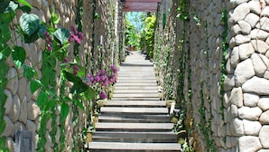 Eine Steintreppe mit einer Pergola darüber, umgeben von Kletterpflanzen und Blumen.