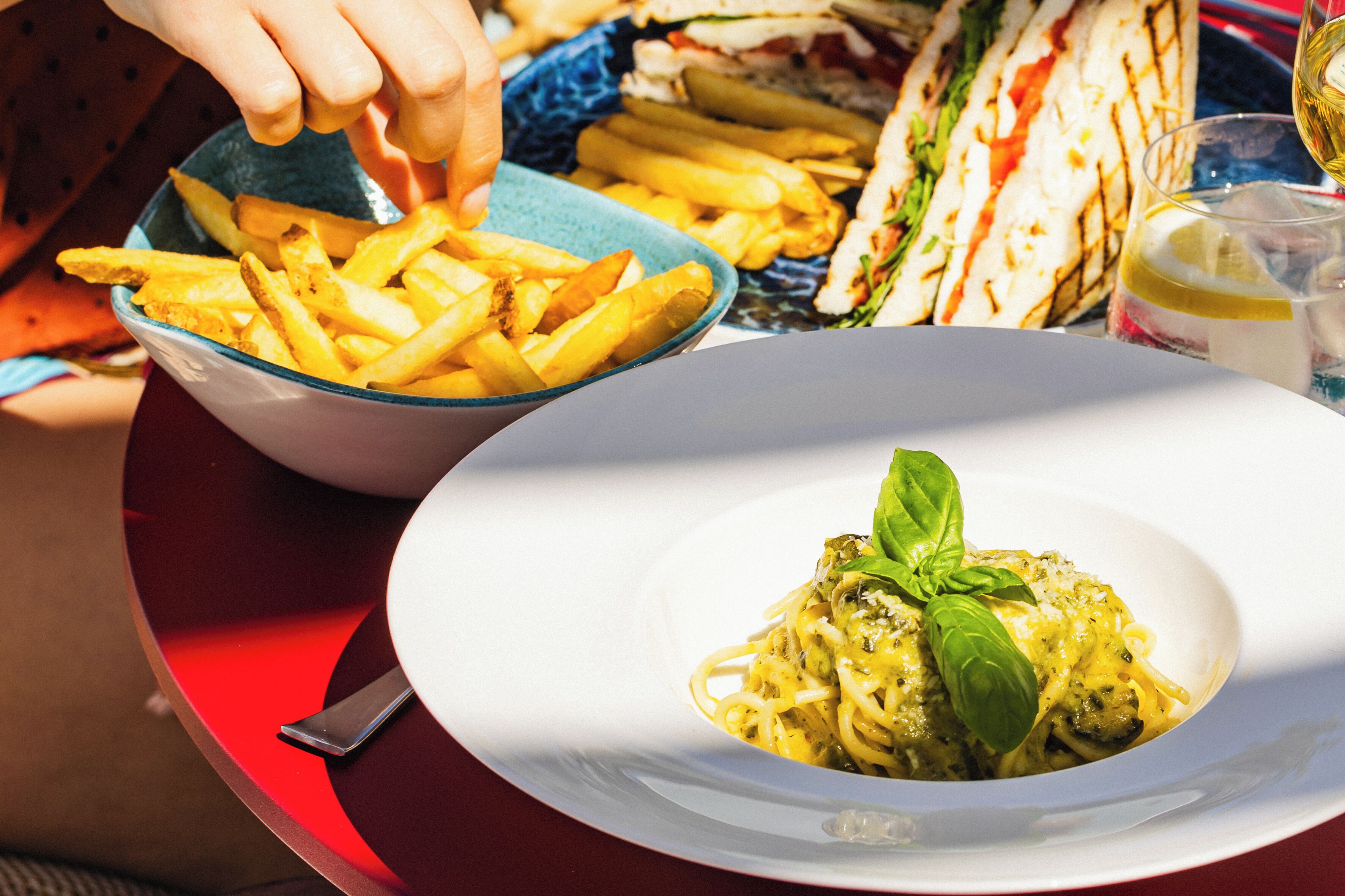 A dining table with a plate of spaghetti and a bowl of French fries.