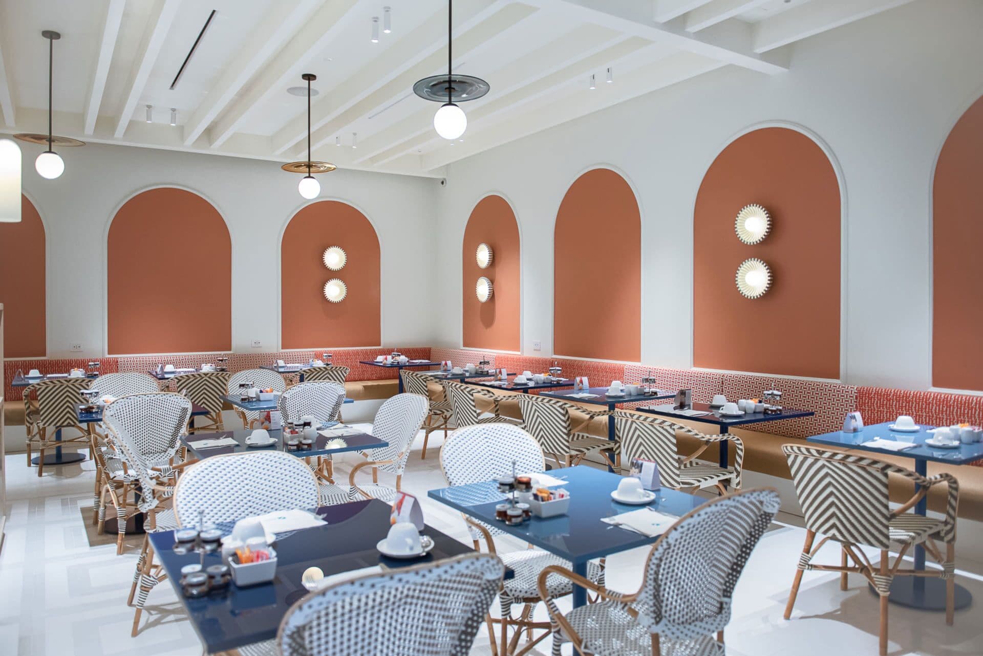 A restaurant with high ceilings, arched walls, and a mix of round and rectangular tables.