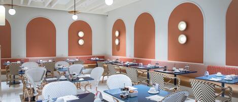 A restaurant with high ceilings, arched walls, and a mix of round and rectangular tables.