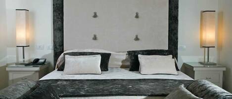 A hotel room with a large bed, two bedside tables, and two lamps.